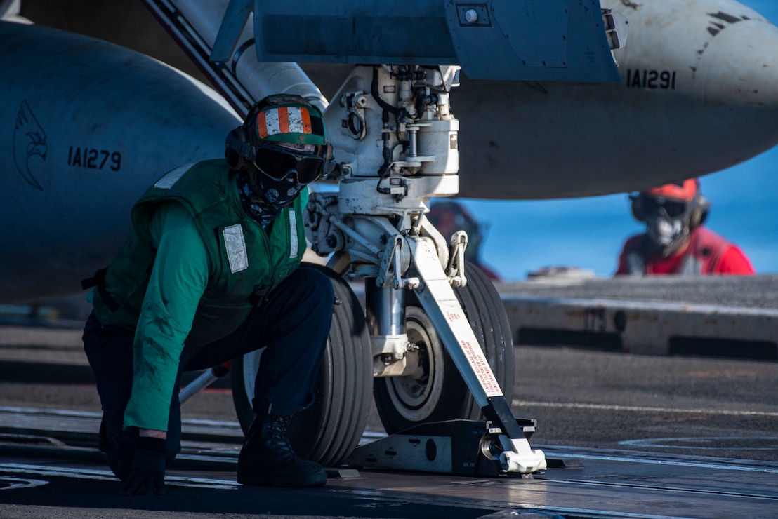 A Sailor awaits confirmation to signal the seating of the catapult onto an F/A-18F Super Hornet from the "Kestrels" of Strike Fighter Squadron (VFA) 137 before launching from the flight deck of the aircraft carrier USS Nimitz (CVN 68) in the Philippine Sea, April 22, 2025.