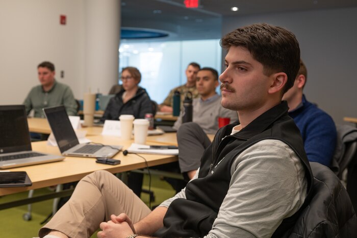 A young man sitting and listening to a presentation