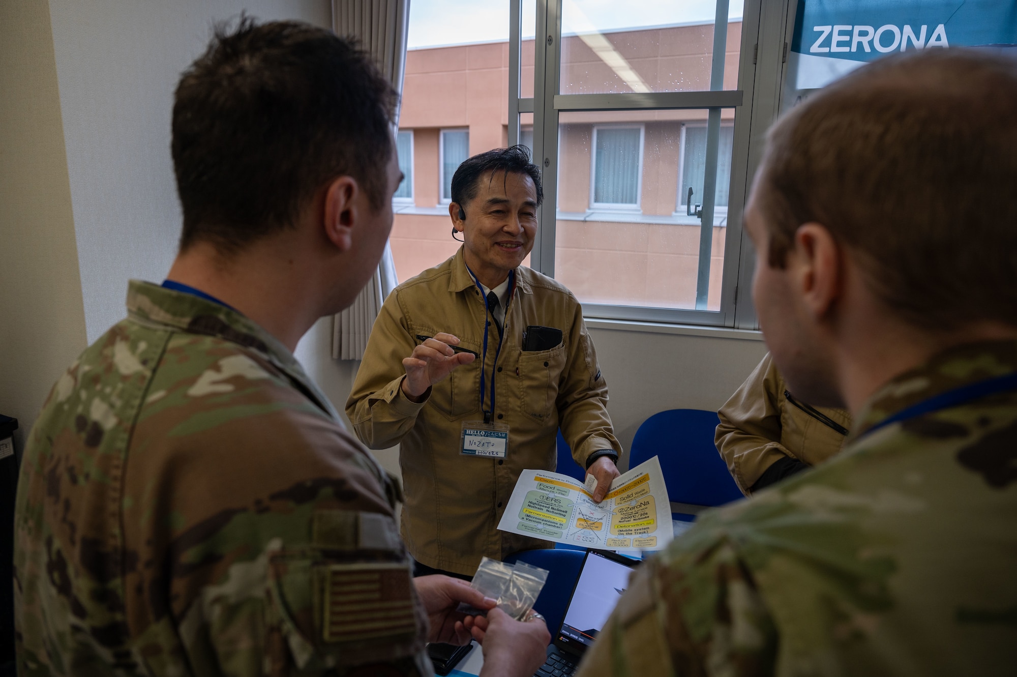 A Japanese company representative discusses product capabilities with U.S. Air Force Airmen during Industry Day at Misawa International Center, April 18, 2025. The event provided a platform for direct engagement between local businesses and 35th Fighter Wing personnel to explore solutions that enhance operational effectiveness and foster long-term collaboration. (U.S. Air Force photo by Senior Airman William Rodriguez)