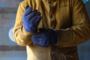 A person is pulling on heavy gloves. the person's face is not visible in the photo.