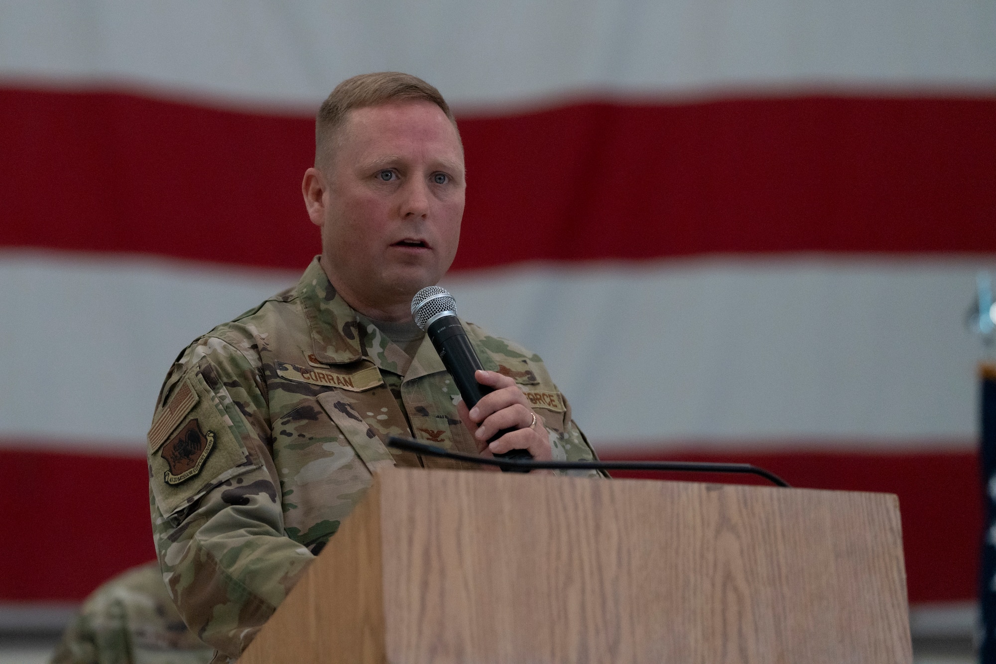 An airman stands at a podium with a microphone.
