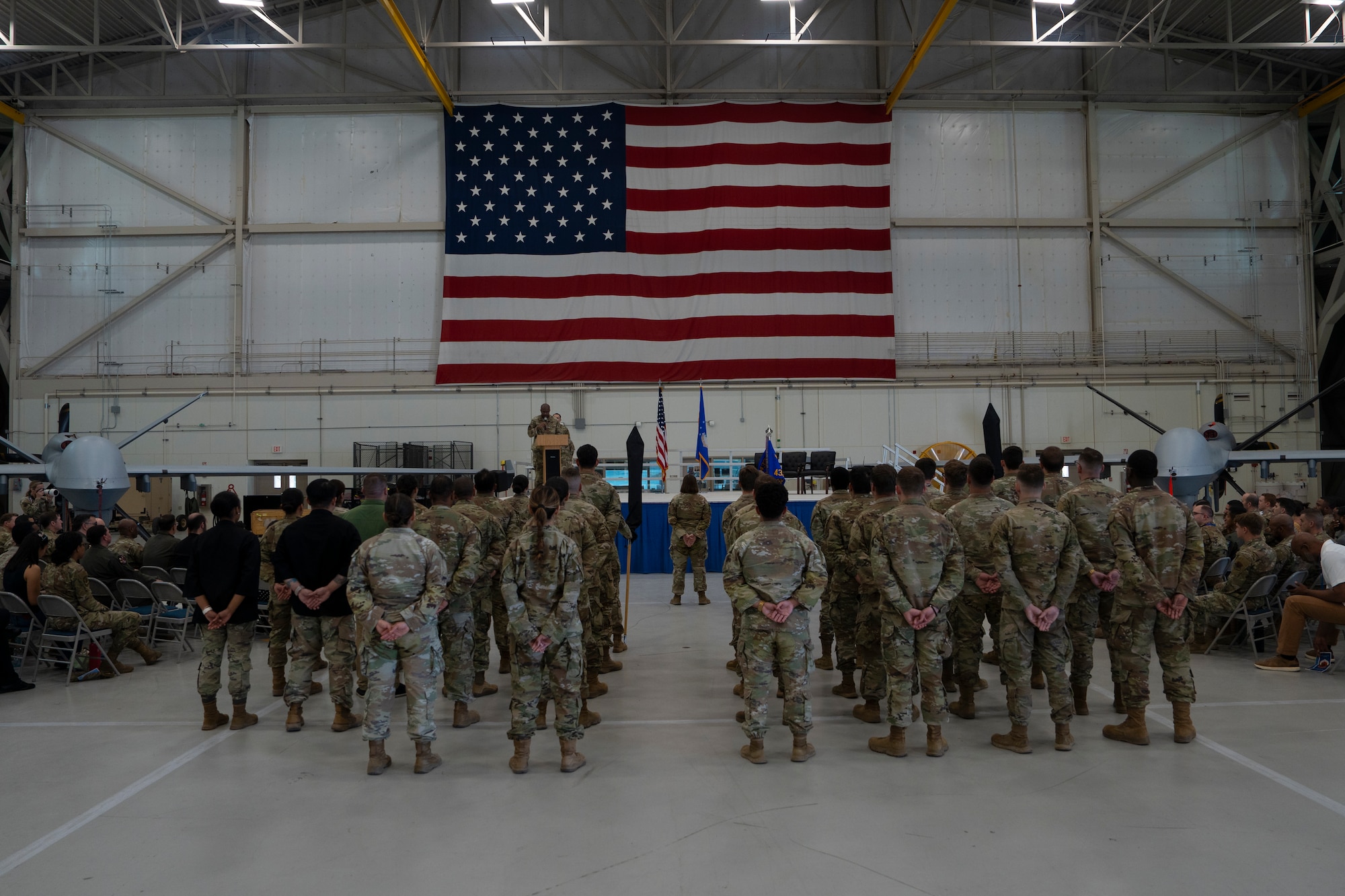 Two squadrons stand at parade rest while facing a stage.