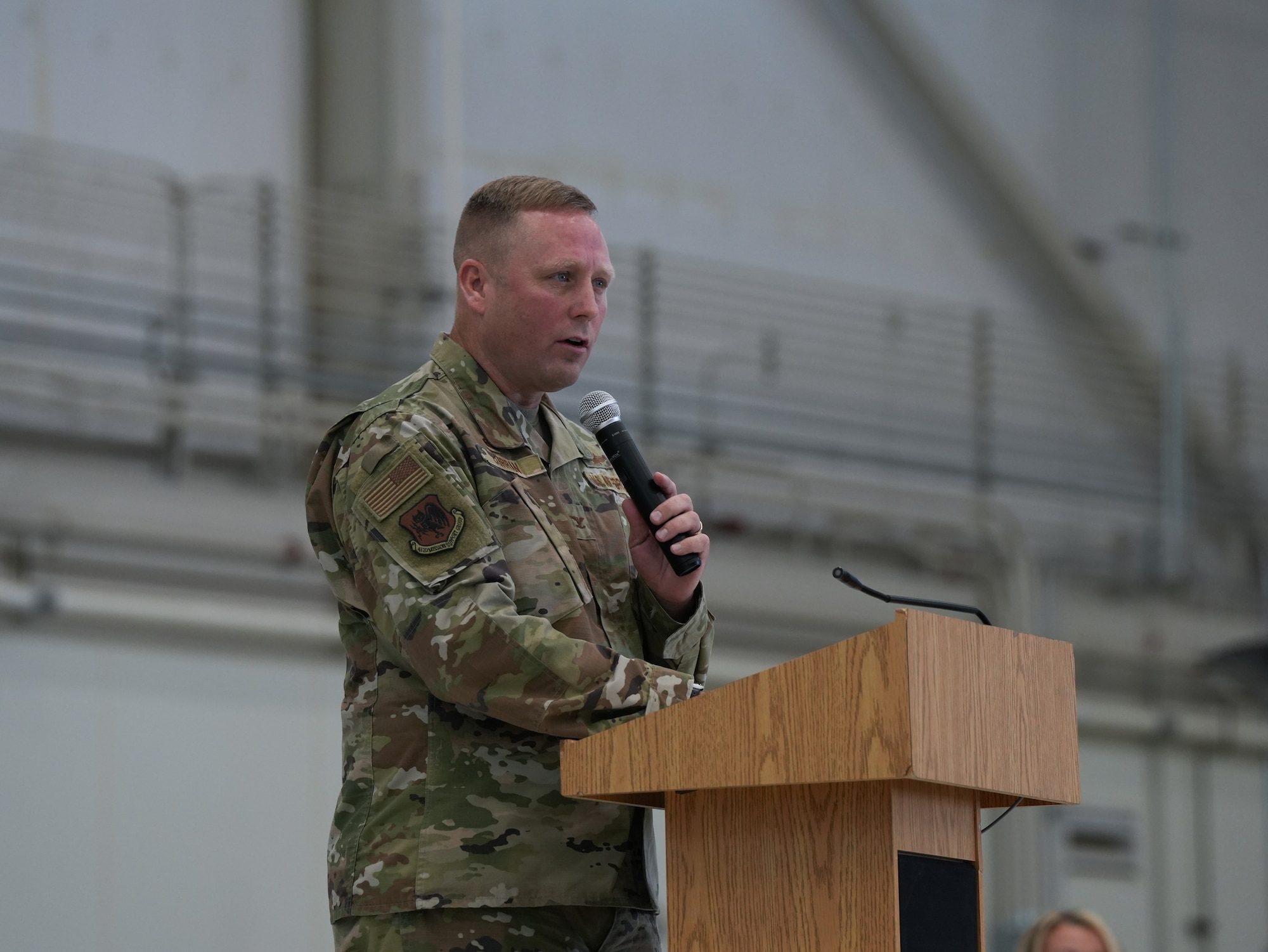 An airman stands at a podium with a microphone.
