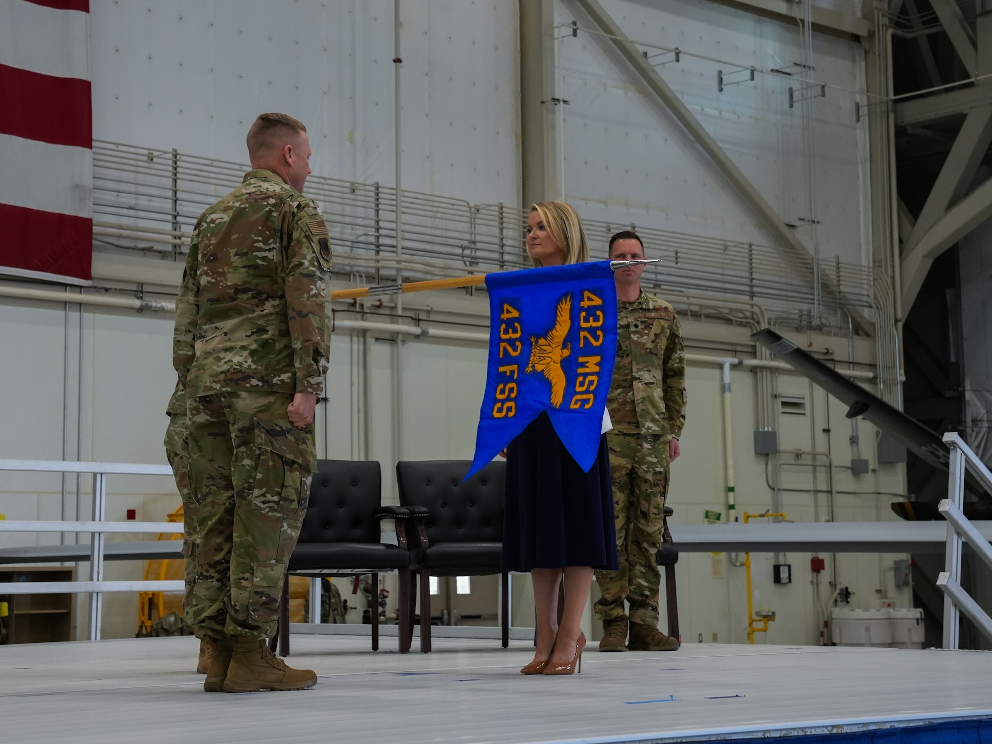 An airman and civilian stand facing each other while a guidon flag is lowered between them.