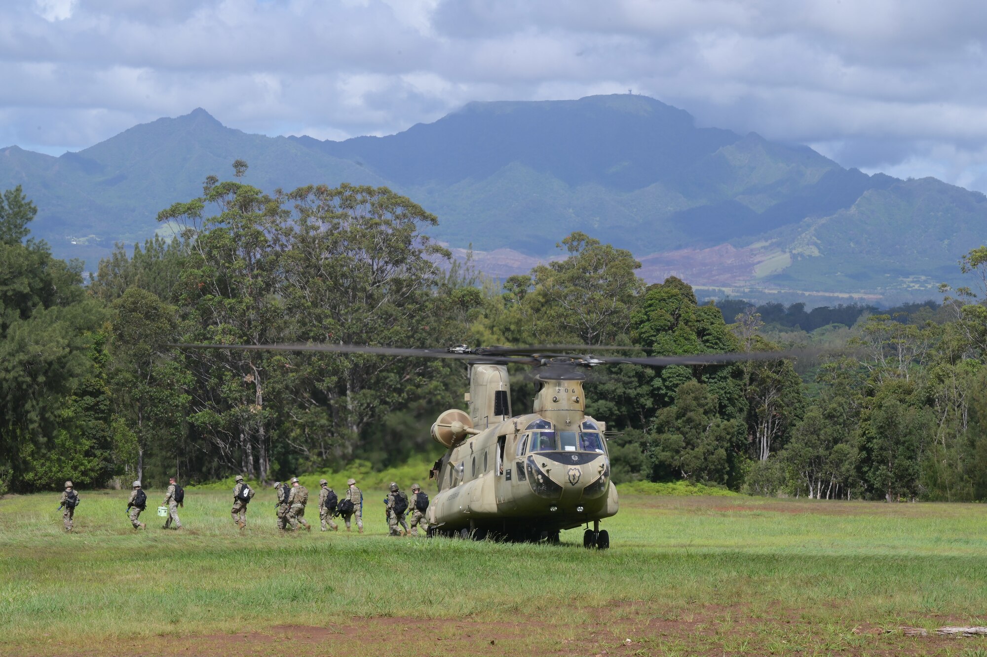 Airmen departing a chinook in a field.