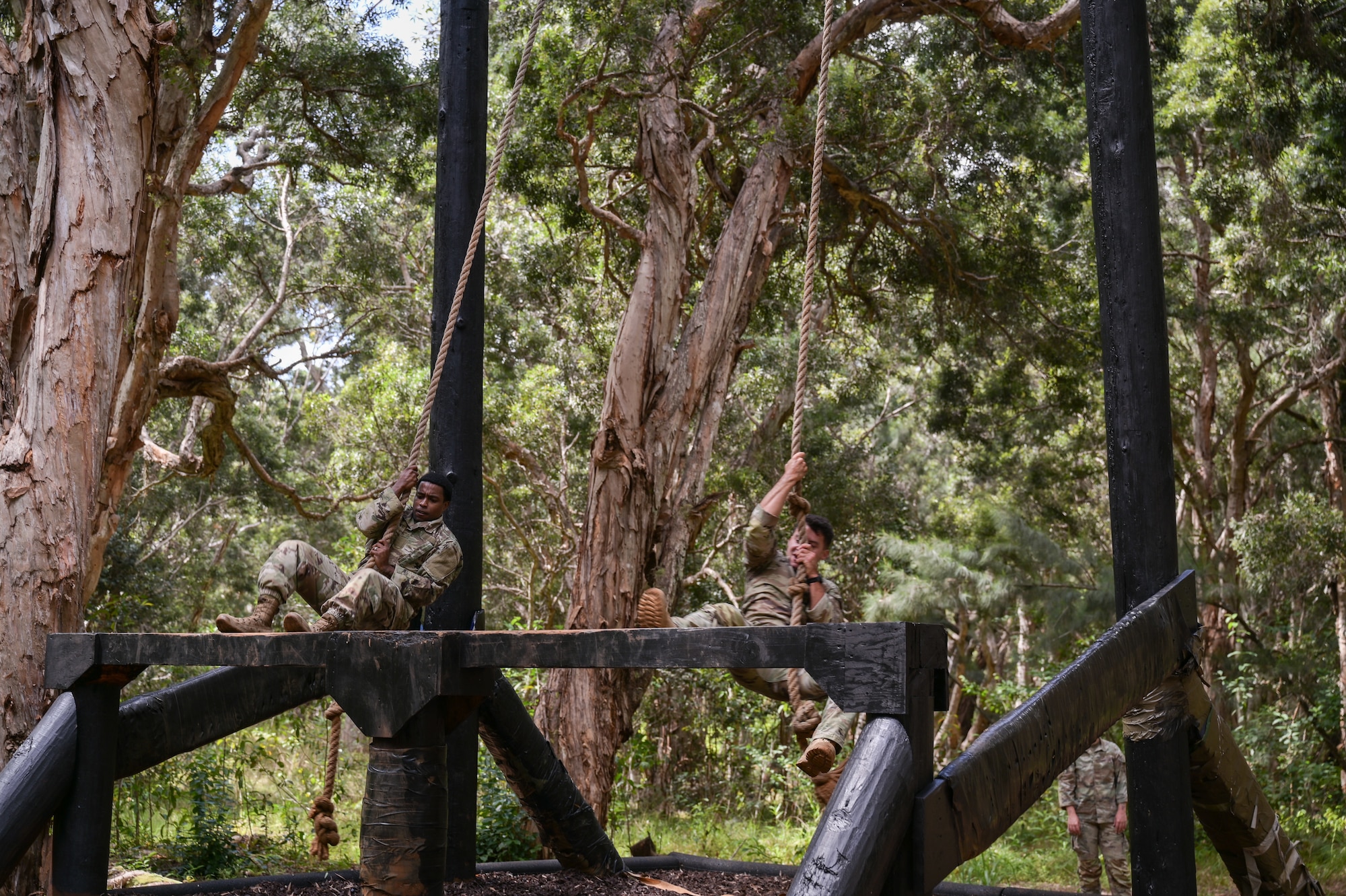 Two Airmen swinging on a rope.