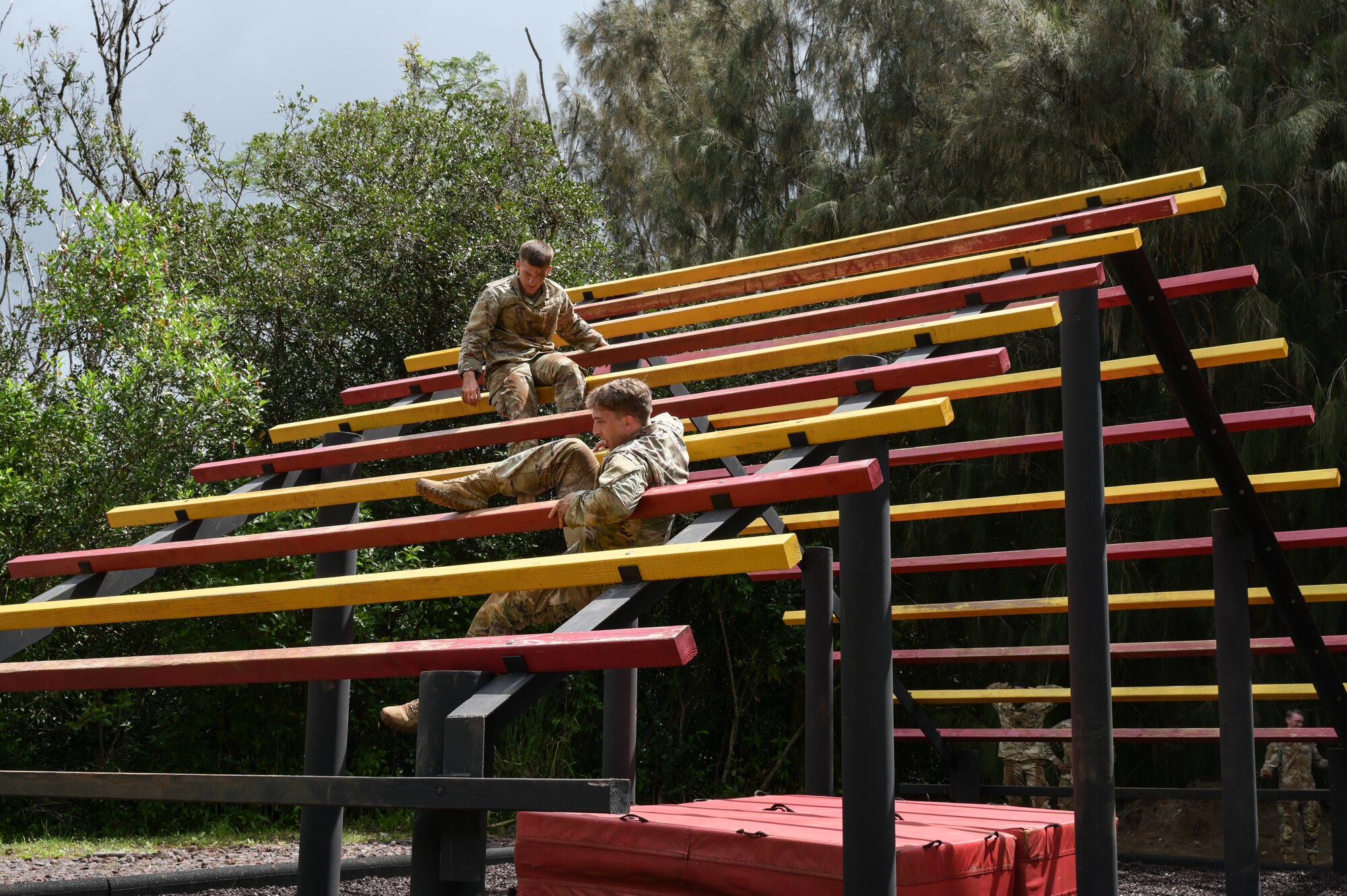 Airmen climbing a multi-colored obstacle.