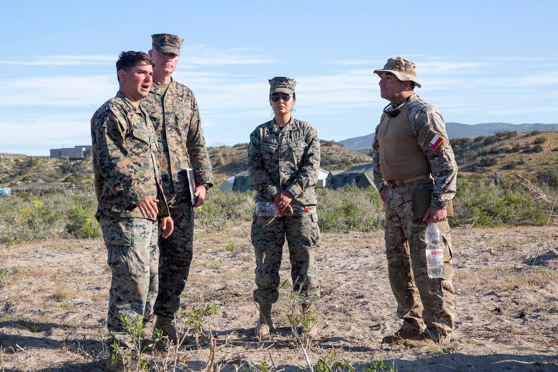 U.S. Marine Corps Col. Ryan Allen (center left), commanding officer of Marine Air Control Group 48, Sgt. Melissa Rivas Casanova (center right), the MACG-48 Non-Commissioned Officer in Charge, and Sgt. Gianny Bizarretty (Left), tactical air defense controller with Marine Air Control Squadron 24, speak with Chilean Marine Col. Francisco Cabezon Gonzalez about the Marine Corps Ground and Air Task Oriented Radar system at the Expeditionary Advanced Base North on Puerto Adlea, Chile, Sept. 6, 2024. They discuss how it will be used in the Amphibious Raid at Puerto Aldea, Chile. The GATOR is being used for Marines to train and to perform counter fires and air defense during the amphibious raid taking place for UNITAS LXV. UNITAS focuses on strengthening our existing regional partnerships and encouraging the establishment of new relationships through the exchange of maritime mission-focused knowledge and expertise. (U. S. Marine Corps photo by Lance Cpl. Payton Goodrich)