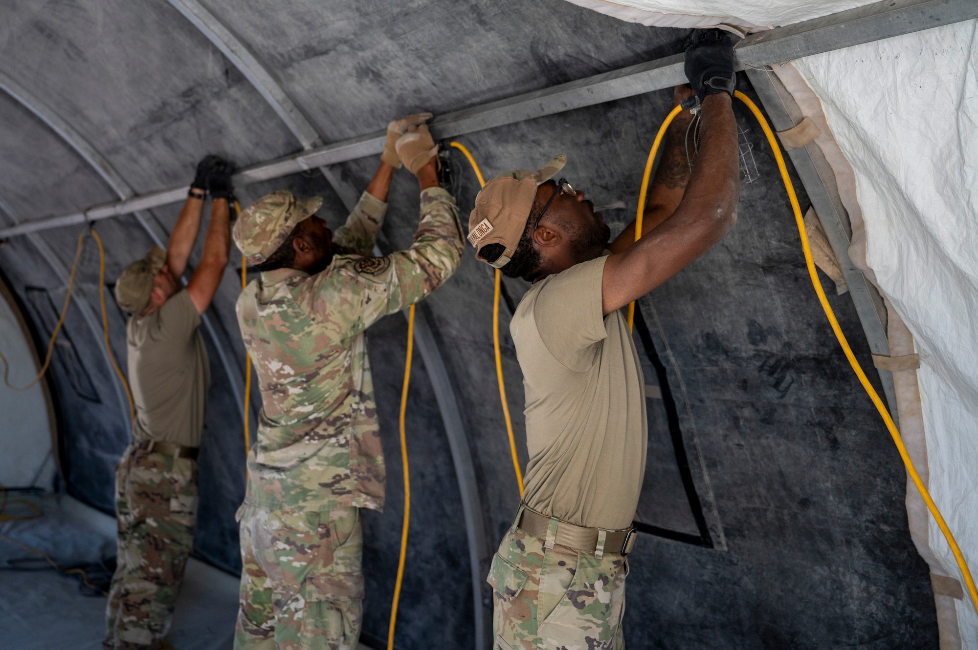U.S. Air Force Airmen assigned to the 22nd Air Task Force, hang an electrical cord during exercise MAGPIE at Tyndall Air Force Base, Florida, April 13, 2025. Exercises like MAGPIE will continue propel the 22nd ATF to operate effectively under stressful conditions in contested environments, resulting in a diverse force of Airmen prepared to undertake mission requirements. (U.S. photo by Airman 1st Class Samantha Thorn)