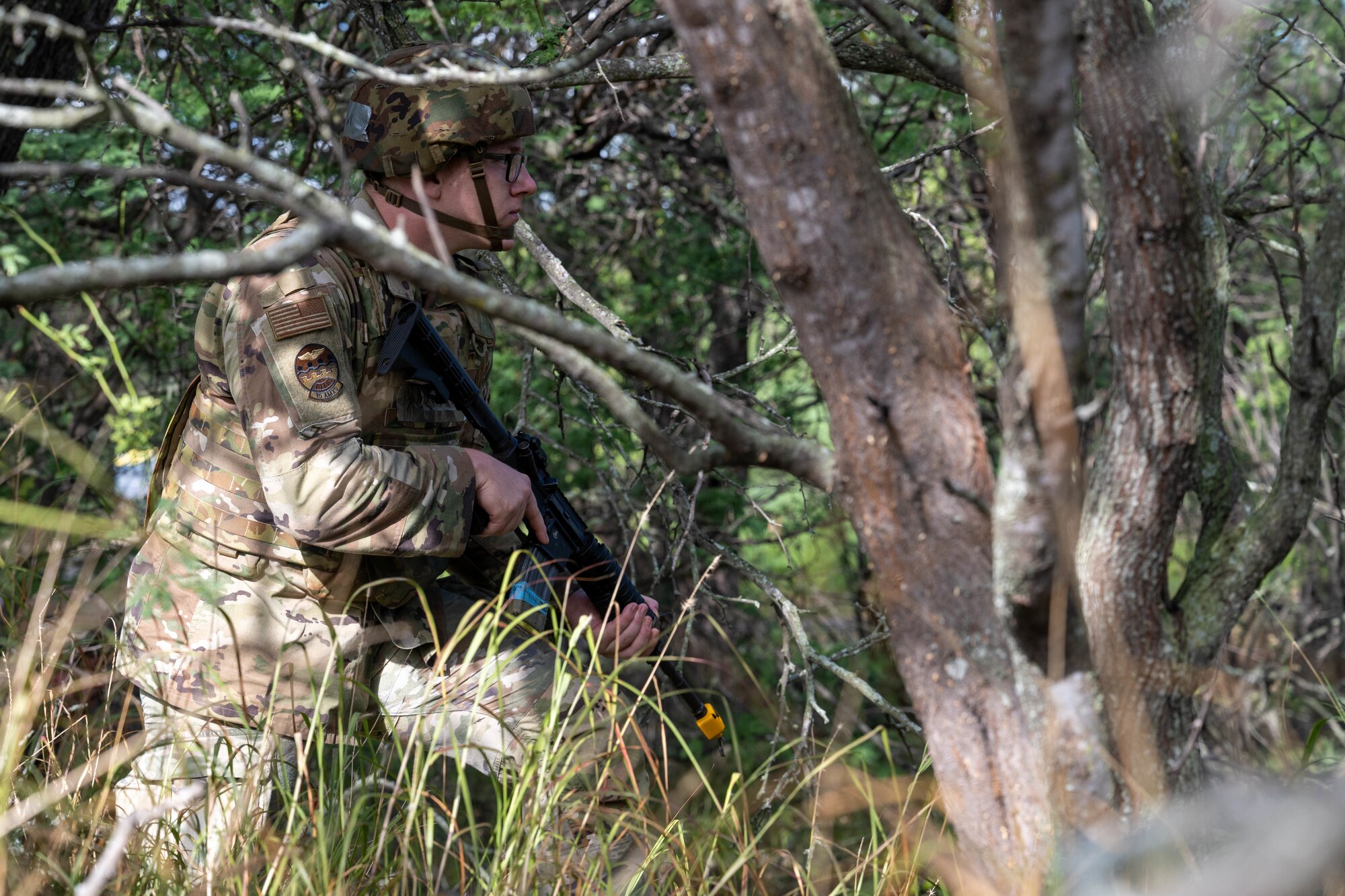 A U.S. Air Force Airmen navigates through the woods with his M4 assault rifle during a training session.