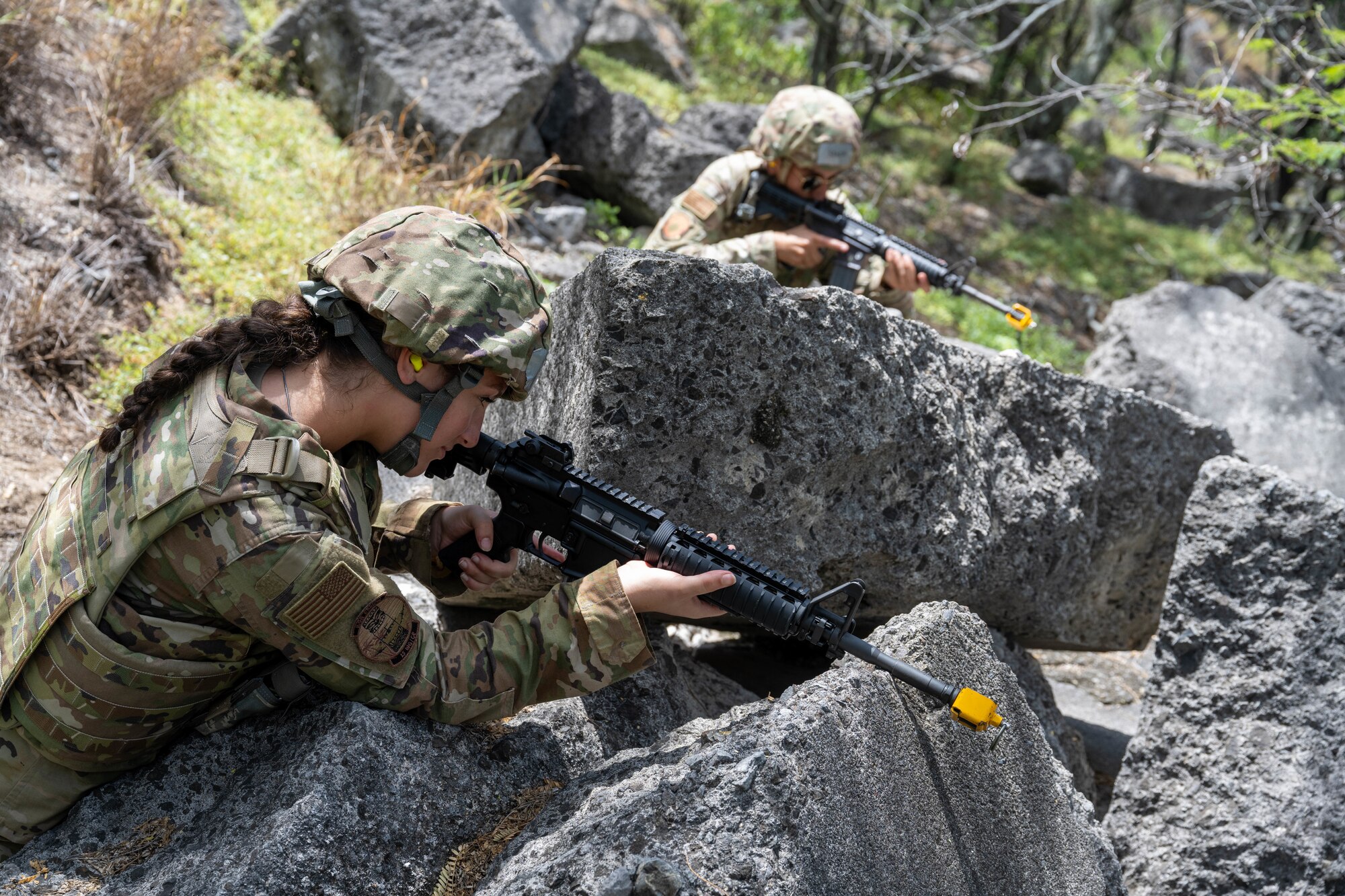 Two U.S. Air Force Airmen hold their positions in the woods with M4 assault rifles during a training session.