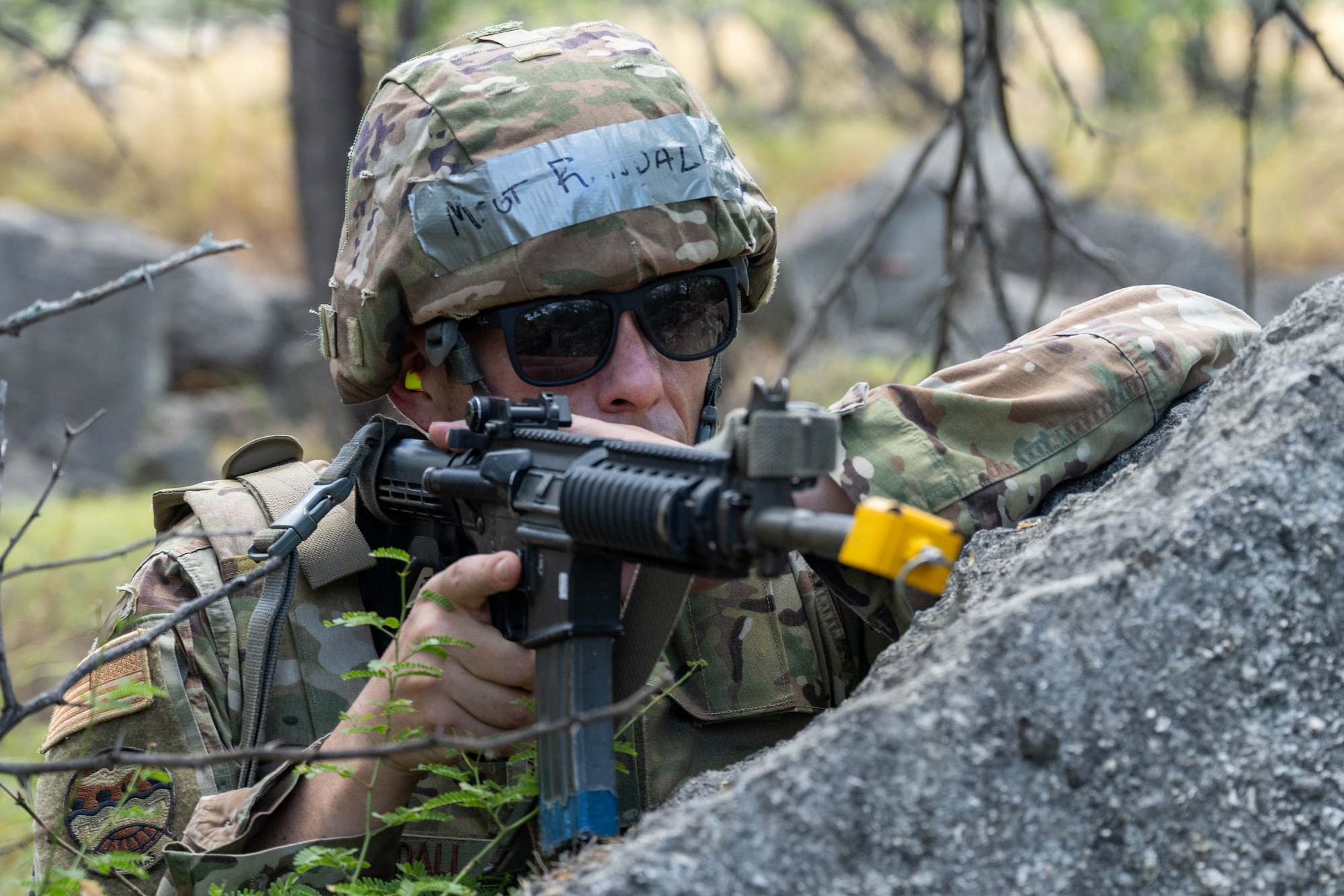 A U.S. Air Force Airmen holds a position in the woods with his M4 assault rifle during training session.