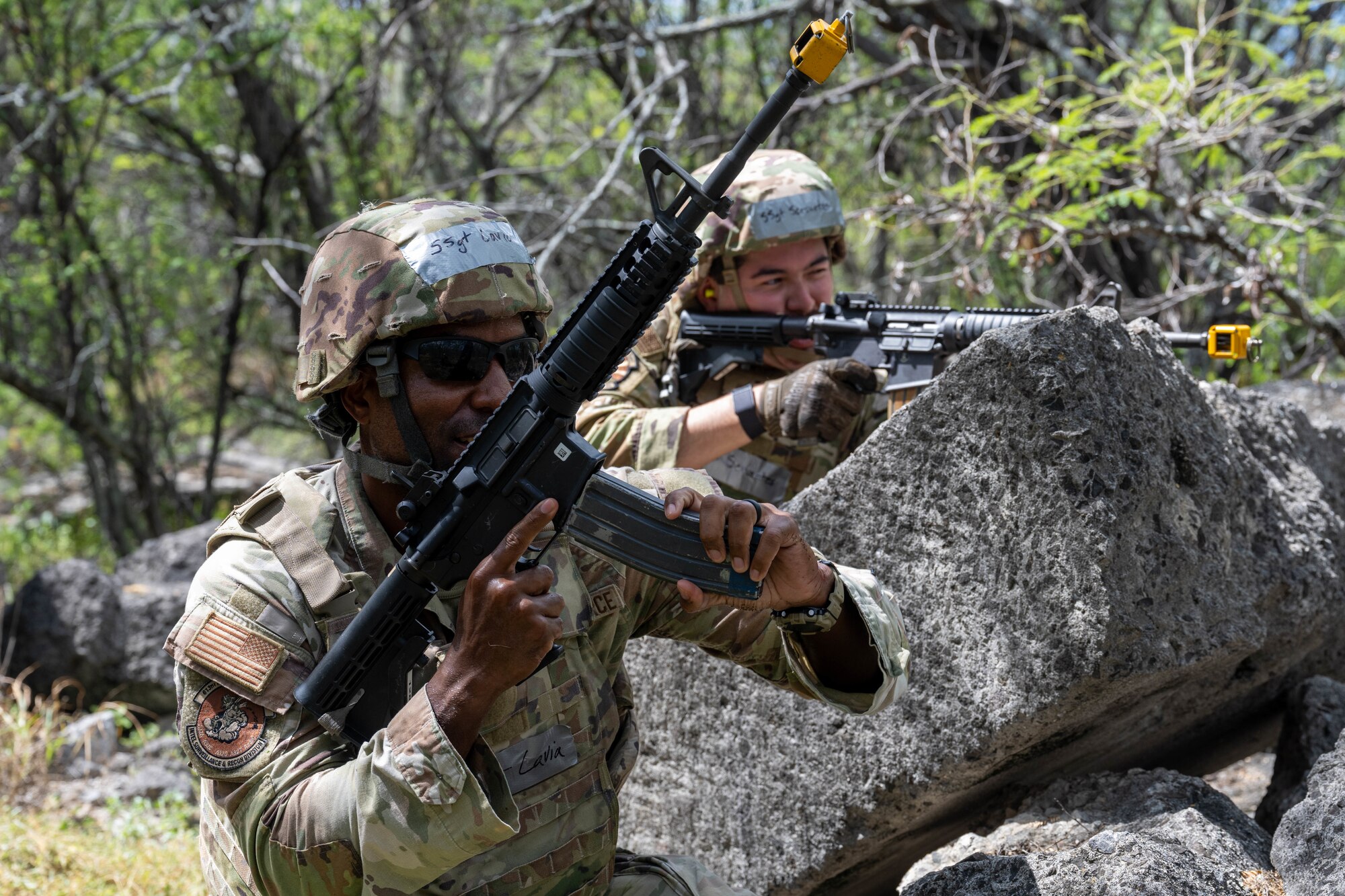 Two U.S. Air Force Airmen hold a position in the woods during a training session.