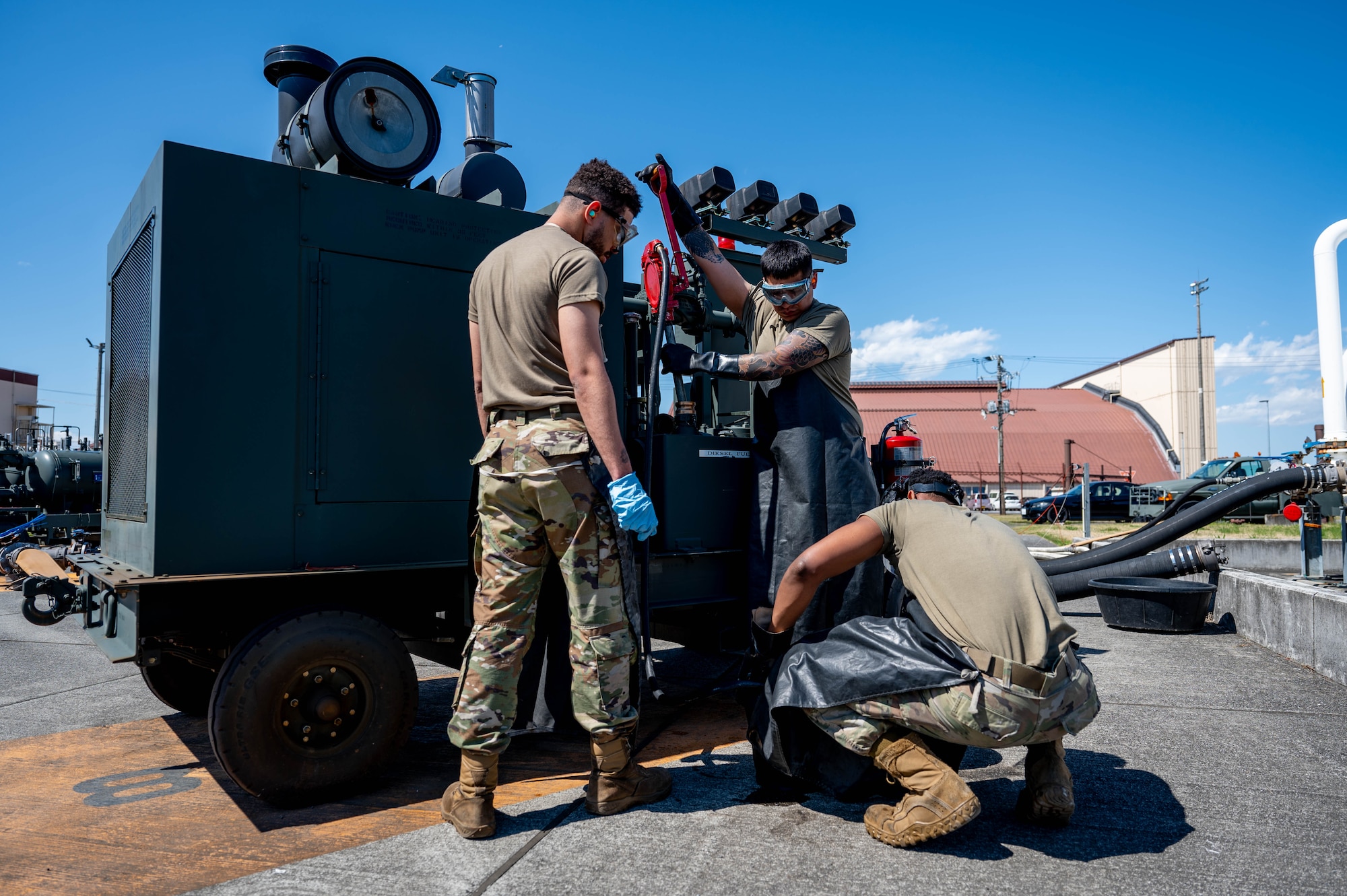 From left, U.S. Air Force Senior Airman Blake Torres, Airman 1st Class Juan Aparicio and Senior Airman Ronald Perry, 374th Logistics Readiness Squadron war reserve technicians, drain a saddle tank.