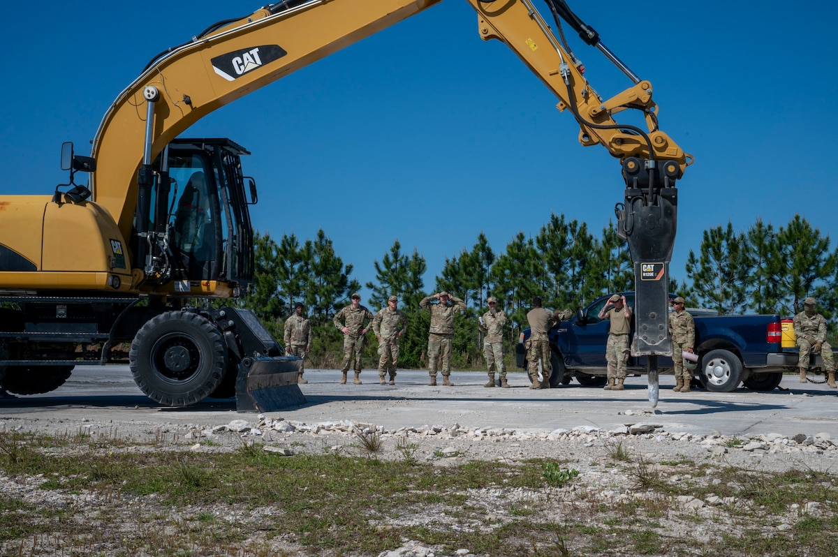 U.S. Air Force Airmen assigned to the 22nd Air Task Force watch as an excavator breaks up the concrete during a MAGPIE exercise at Tyndall Air Force Base, Florida, April 14, 2025. The 22nd ATF participated in rigorous exercises and diverse training programs to ensure that ATFs are fully prepared to execute assigned missions. (U.S. photo by Airman 1st Class Samantha Thorn)