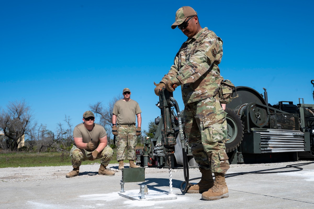 U.S. Air Force Airmen assigned to the 22nd Air Task Force, utilize a power drill to anchor a Mobile Arresting Aircraft System during exercise MAGPIE at Tyndall Air Force Base, Florida, April 14, 2025. The 22nd ATF participated in rigorous exercises and diverse training programs to ensure that ATFs are fully prepared to execute assigned missions. (U.S. photo by Airman 1st Class Samantha Thorn)