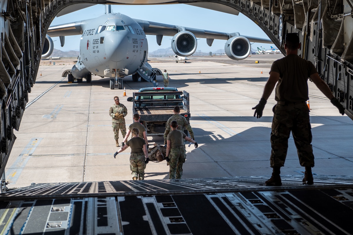 Reserve Citizen Airmen, 944th Aeromedical Staging Squadron, transport a litter patient off a C-17 Globemaster III during an aeromedical evacuation training event at Phoenix-Goodyear Airport in Goodyear, Ariz., April 17, 2025. The training provided valuable hands-on experience in managing patient care under flight conditions, ensuring the team is ready for real-world medical missions.  (U.S. Air Force photo by Staff Sgt. Alexis Orozco)