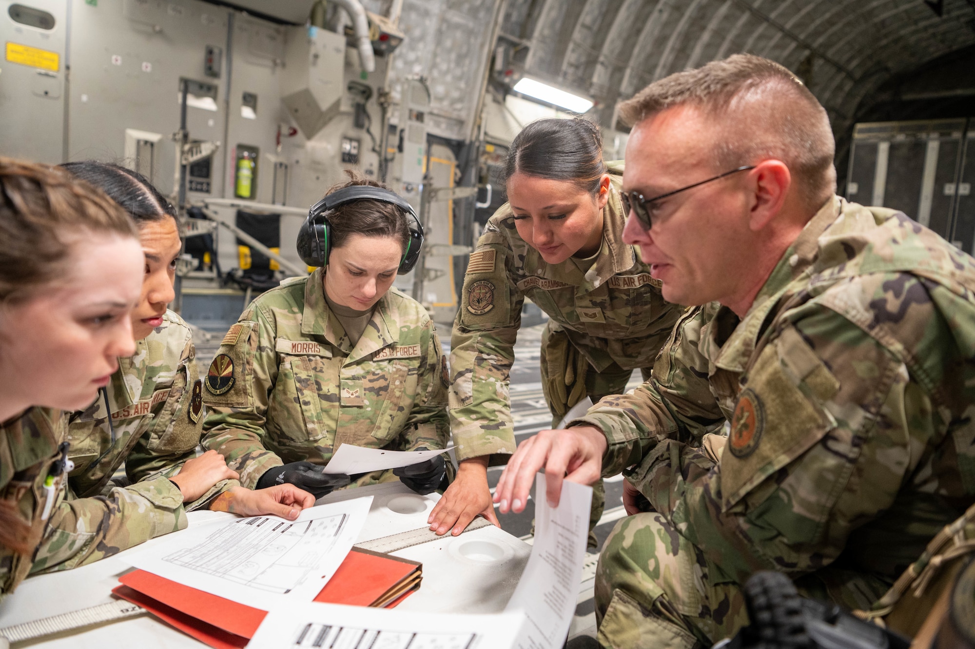 Reserve Citizen Airmen, 944th Aeromedical Staging Squadron, review training mission materials during a aeromedical evacuation training event aboard a C-17 Globemaster III flying nearby Nellis Air Force Base, Nev., April 16, 2025. The joint exercise with Army National Guard and Critical Care Air Transport Team specialists ensured the team was equipped with the knowledge needed for complex medical evacuation operations. (U.S. Air Force photo by Staff Sgt. Alexis Orozco