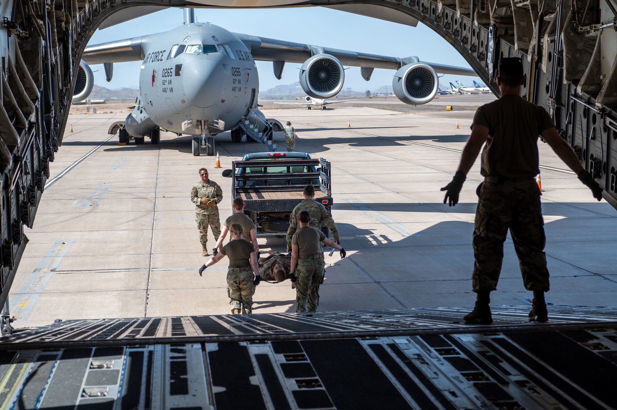 Reserve Citizen Airmen, 944th Aeromedical Staging Squadron, transport a litter patient off a C-17 Globemaster III during an aeromedical evacuation training event at Phoenix-Goodyear Airport in Goodyear, Ariz., April 17, 2025. The training provided valuable hands-on experience in managing patient care under flight conditions, ensuring the team is ready for real-world medical missions.  (U.S. Air Force photo by Staff Sgt. Alexis Orozco)