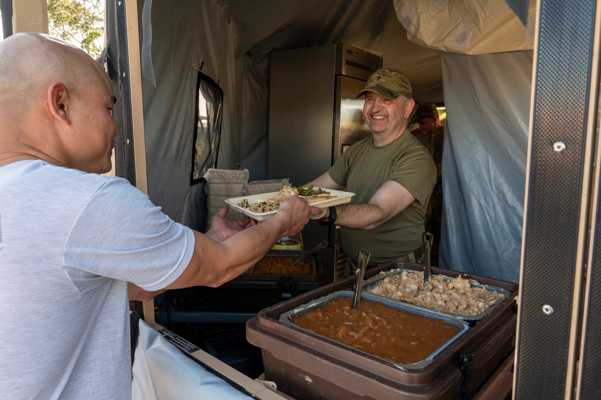 U.S. Air Force Maj. Dariusz Barna, a deputy wing chaplain assigned to the 22nd Air Task Force, serves food to Airmen during a Silver Flag exercise at Tyndall Air Force Base, Florida, April 9, 2025. This exercise was designed to evaluate and enhance the operational skills of 22nd ATF, ensuring that they are an agile and responsive asset within our Air Force. (U.S. photo by Airman 1st Class Samantha Thorn)