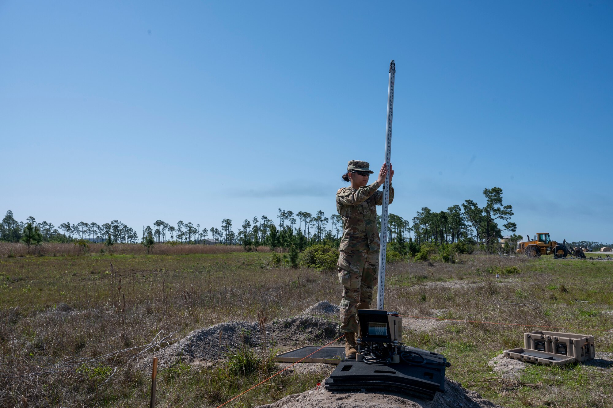 U.S. Air Force Airman Jocelyn Hansen, a fuel distribution operator assigned to the 22nd Air Task Force, holds a measurement device in place for the survey total station during a Silver Flag exercise at Tyndall Air Force Base, Florida, April 9, 2025. This exercise was designed to evaluate and enhance the operational skills of 22nd Air Task Force, ensuring that they are an agile and responsive asset within our Air Force. (U.S. photo by Airman 1st Class Samantha Thorn)