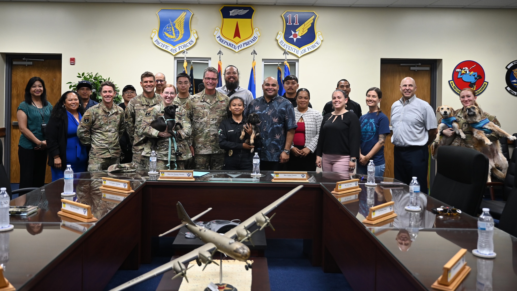 Attendees and dogs pose for a group photo commemorating the Boonie Dog support agreement signing at Andersen Air Force Base, Guam, April 24, 2025. This ceremony was the first Intergovernmental Support Agreement (IGSA) with Andersen AFB and the Guam Department of Agriculture. (U.S. Air Force photo by Airman 1st Class Adasha Williams)