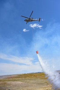 A HH-60M Black Hawk, assigned to Wyoming Army Aviation Support Facility, releases water during an interagency bucket drop training at Camp Guernsey, Wyoming, on April 16, 2025.