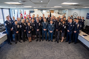 Airmen and Gaurdians stand together in service dress for a group photo.
