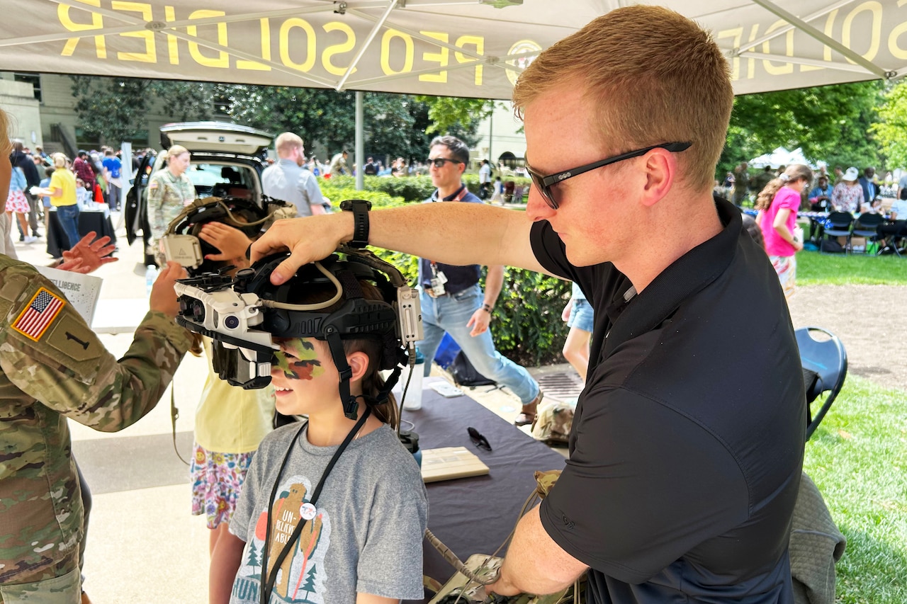 A man in casual attire puts equipment over the head of a child wearing face paint.