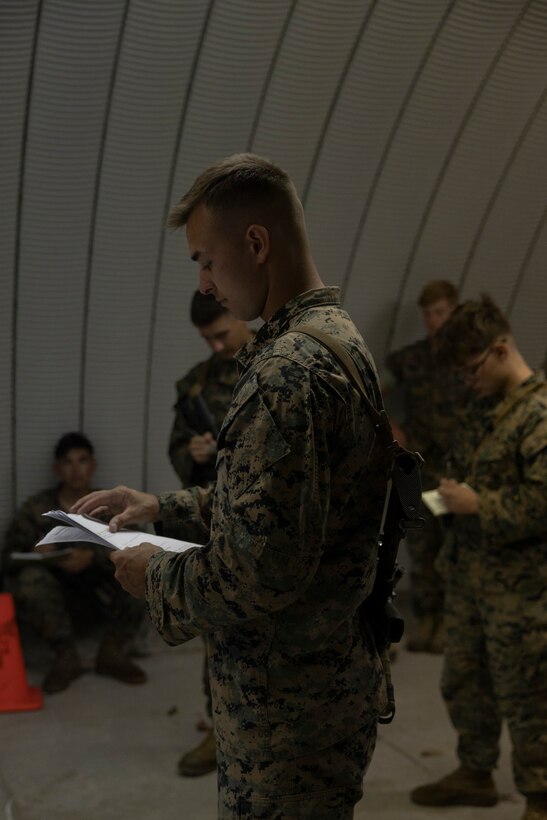 U.S. Marine Corps Cpl. John O’Connor, a native of Pennsylvania and a low-altitude air-defense gunner with 2nd Low-Altitude Air Defense (LAAD) Battalion, Marine Air Control Group (MACG) 28, 2nd Marine Aircraft Wing (MAW), reviews his notes while briefing Marines during a Base Defense Zone (BDZ) exercise at Marine Corps Auxiliary Landing Field Bogue, North Carolina, June 11, 2024. Marines from 2nd LAAD, MACS-24 and Marine Wing Support Squadron (MWSS) 271 executed this exercise to enhance confidence and proficiency in BDZ operations. (U.S. Marine Corps photo by Lance Cpl. Bryan Giraldo)