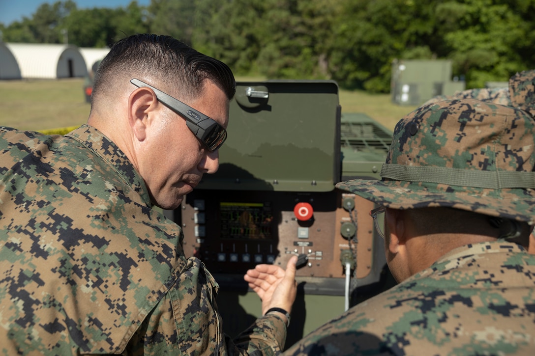 U.S. Marine Corps Master Sgt. Richard Belfer, a native of New York and a utility chief, teaches Lance Cpl. Ulises Jaimes, a native of Texas and an engineer equipment mechanic, both with Marine Air Control Squadron (MACS) 24, 4th Marine Aircraft Wing (MAW), how to operate a MEP-1070 generator set during a Base Defense Zone (BDZ) exercise at Marine Corps Auxiliary Landing Field Bogue, North Carolina, June 11, 2024. Marines from 2nd Low-Altitude Air Defense (LAAD) Battalion, MACS-24 and Marine Wing Support Squadron (MWSS) 271 executed this exercise to enhance confidence and proficiency in BDZ operations. (U.S. Marine Corps photo by Lance Cpl. Bryan Giraldo)