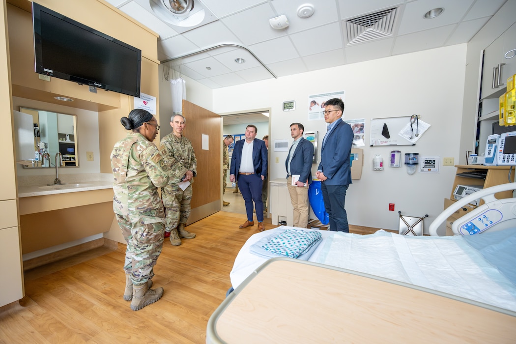 men and women stand inside hospital room