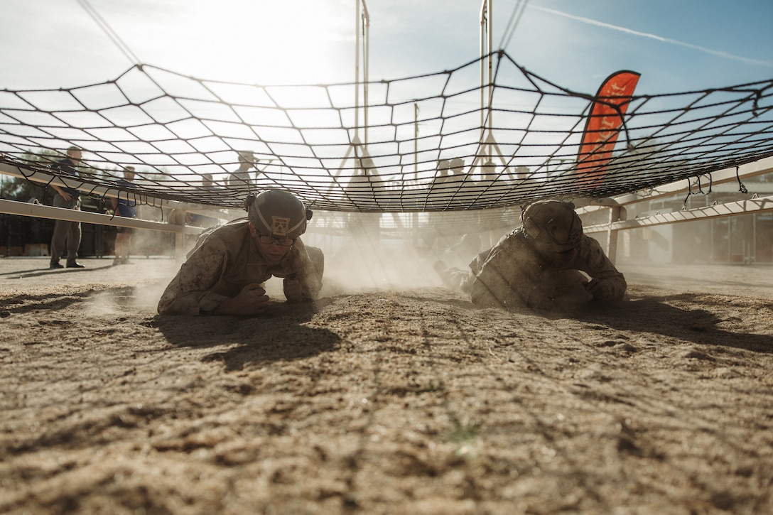 U.S. Marines with 1st Battalion, 7th Marine Regiment, 1st Marine Division, low crawl through an obstacle course during their final evaluation as part of a 7th Marine Regiment Infantry Rifle Squad Competition at Marine Corps Air-Ground Combat Center, Twentynine Palms, California, Dec. 19, 2024. The 7th Marine Regiment Infantry Rifle Squad Competition assesses tactical proficiency and determines the Regiment's most capable squad under simulated combat conditions. Designed to evaluate tactics, techniques, and procedures, the event also promotes professional growth and camaraderie through healthy competition. (U.S. Marine Corps photo by Lance Cpl. Richard PerezGarcia)