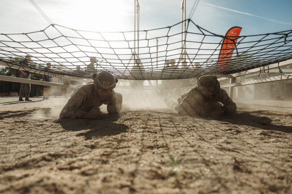 U.S. Marines with 1st Battalion, 7th Marine Regiment, 1st Marine Division, low crawl through an obstacle course during their final evaluation as part of a 7th Marine Regiment Infantry Rifle Squad Competition at Marine Corps Air-Ground Combat Center, Twentynine Palms, California, Dec. 19, 2024. The 7th Marine Regiment Infantry Rifle Squad Competition assesses tactical proficiency and determines the Regiment's most capable squad under simulated combat conditions. Designed to evaluate tactics, techniques, and procedures, the event also promotes professional growth and camaraderie through healthy competition. (U.S. Marine Corps photo by Lance Cpl. Richard PerezGarcia)