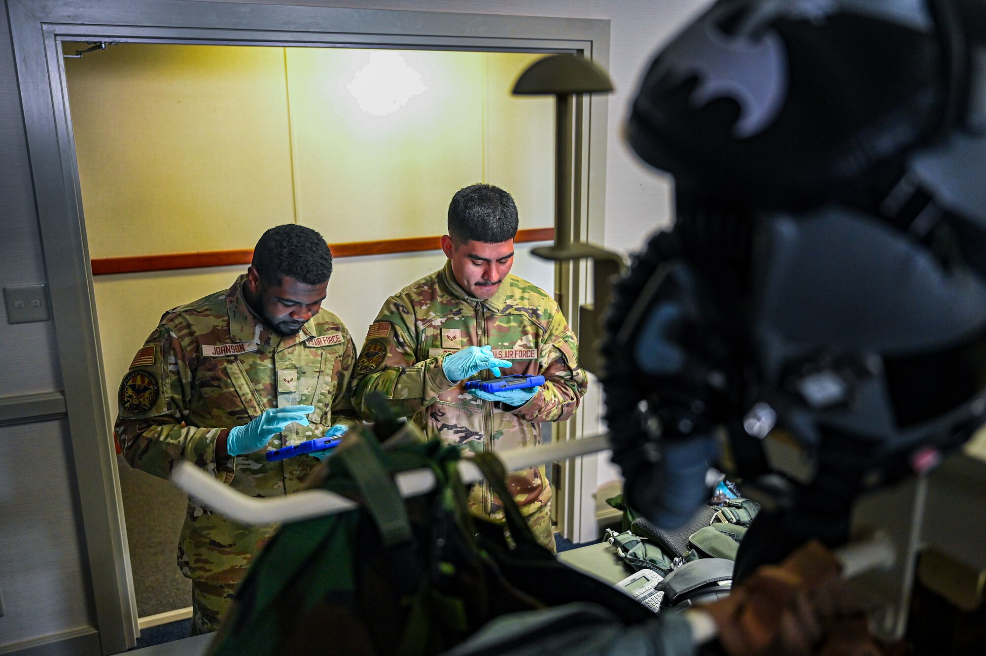 U.S. Air Force Airman 1st Class Juwan Johnson, 9th Expeditionary Bomb Squadron aircrew flight equipment technician, and Senior Airman Jacob Gomez, 9th EBS AFE technician, perform an inspection on a PCU 15P harness and HGU 55P helmet before the aircrew takes off for a Bomber Task Force mission at Misawa Air Base, Japan, April 21, 2025. The Bomber Task Force missions conducted by USSTRATCOM help ensure global security by proving the ability to show deterrence in various locations, while also enhancing the military readiness of allied and partner forces. (U.S. Air Force photo by Airman 1st Class Mattison Cole)