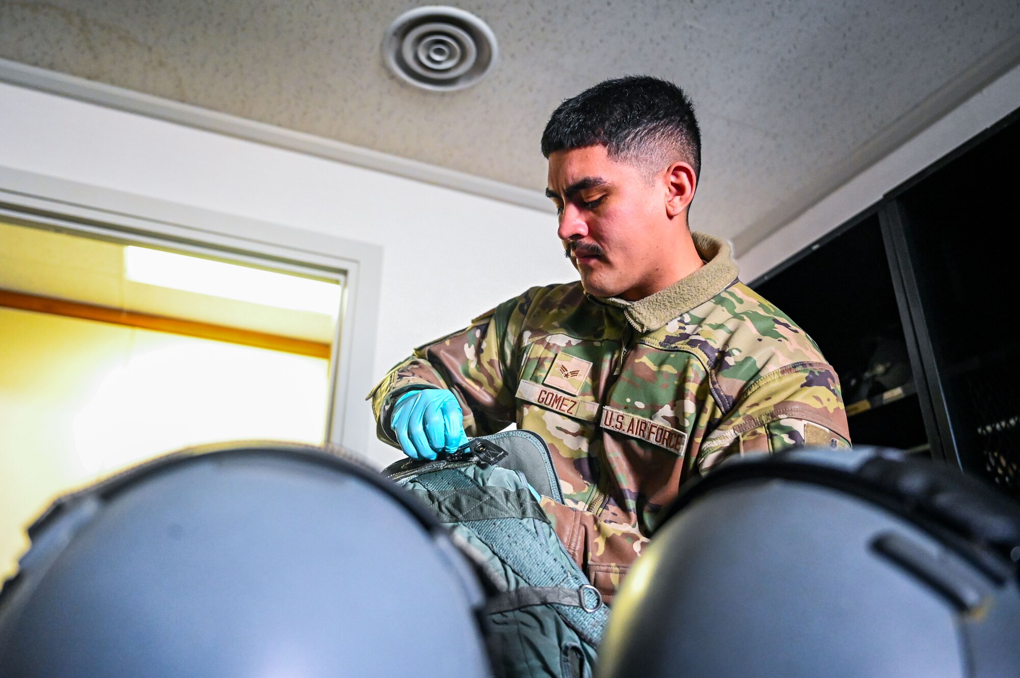 U.S. Air Force Airman Senior Airman Jacob Gomez, 9th Expeditionary Bomb Squadron aircrew flight equipment technician, performs an inspection on a PCU 15P harness and HGU 55P helmet before the aircrew takes off for a Bomber Task Force mission at Misawa Air Base, Japan, April 21, 2025. The 9th EBS AFE members follow all safety precautions during equipment inspections to ensure it is operational and up to par to support the BTF mission. BTF 25-2 provides opportunities to train and work with our allies and partners in joint and combined operations. (U.S. Air Force photo by Airman 1st Class Mattison Cole)
