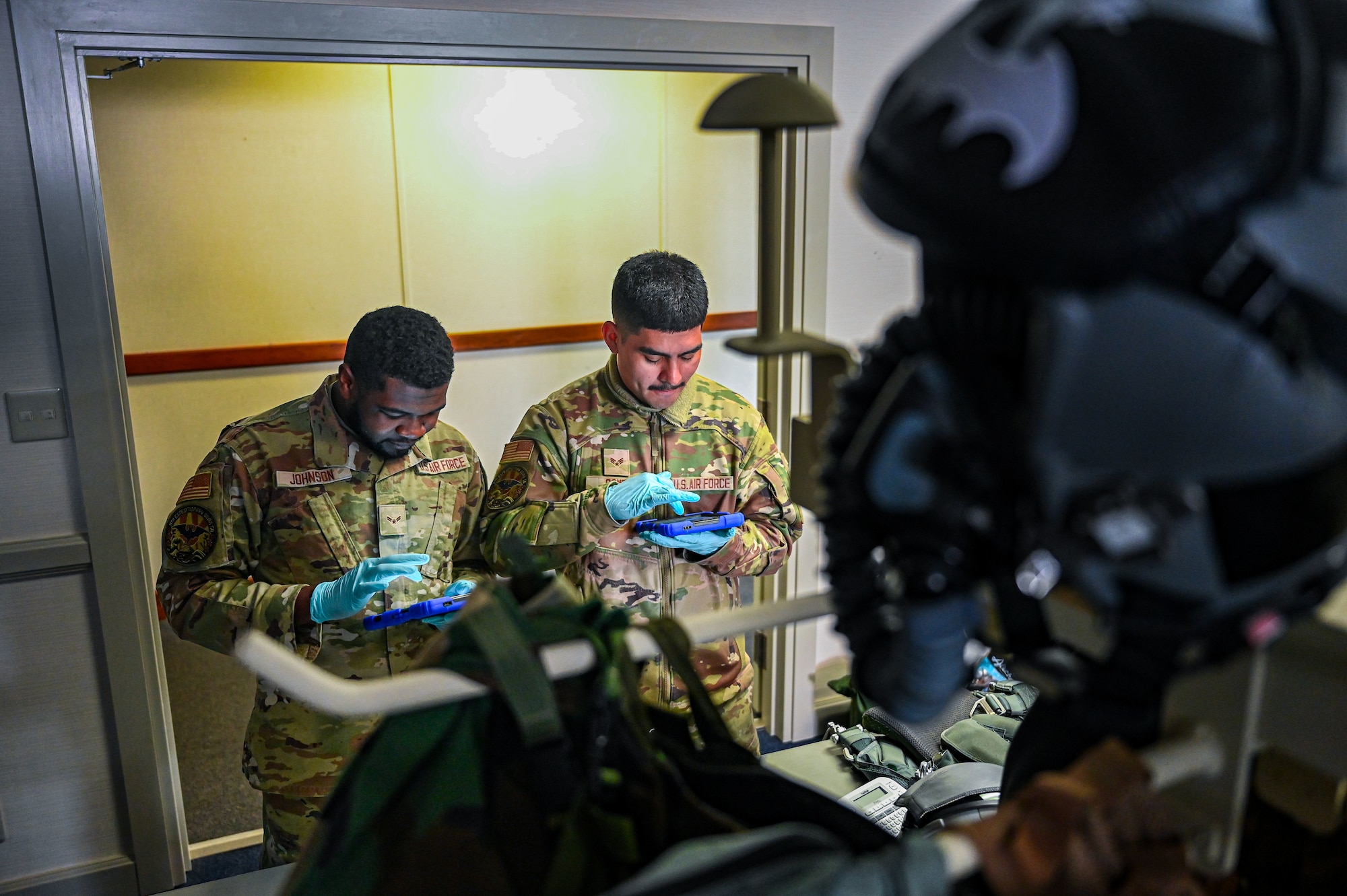 U.S. Air Force Airman 1st Class Juwan Johnson, 9th Expeditionary Bomb Squadron aircrew flight equipment technician, and Senior Airman Jacob Gomez, 9th EBS AFE technician, perform an inspection on a PCU 15P harness and HGU 55P helmet before the aircrew takes off for a Bomber Task Force mission at Misawa Air Base, Japan, April 21, 2025. The Bomber Task Force missions conducted by USSTRATCOM help ensure global security by proving the ability to show deterrence in various locations, while also enhancing the military readiness of allied and partner forces. (U.S. Air Force photo by Airman 1st Class Mattison Cole)