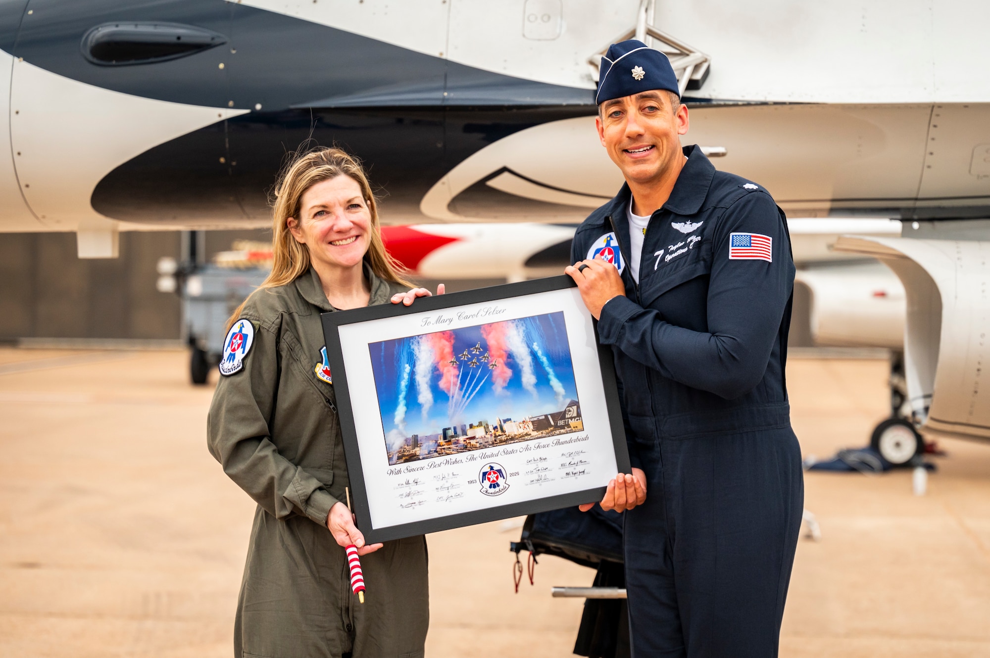 U.S. Air Force Lt. Col. Taylor Wight, right, Thunderbird Seven, Director of Operations for the U.S. Air Force Air Demonstration Squadron "Thunderbirds", presents Cari Selzer, left, Hometown Hero participant, with memorabilia after completing an incentive flight at Dyess Air Force Base, Texas, April 18, 2025. Selzer actively volunteers at the Union Gospel Mission in Fort Worth, serving meals to the homeless, organizing group outings for her colleagues, and creating special events for families in need. (U.S. Air Force photo by Staff Sgt. Leon Redfern)