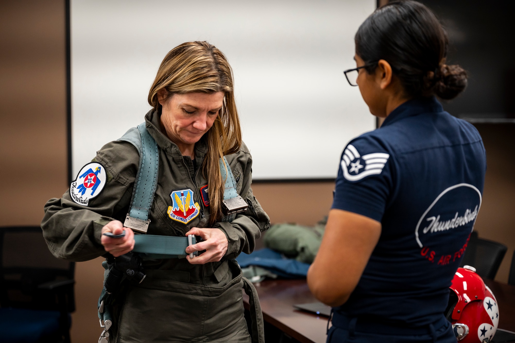 Cari Selzer, Hometown Hero participant, tightens flight harnesses with assistance from U.S. Air Force Staff Sgt. Kimberly Sanchez Vega, Aircrew Flight Equipment (AFE) technician and lead trainer for the U.S. Air Force Air Demonstration Squadron "Thunderbirds" AFE team, before an incentive flight at Dyess Air Force Base, Texas, April 18, 2025. Selzer has dedicated her time and skills to international medical missions, both in Kenya and the Philippines, providing essential care and education to hundreds in need. (U.S. Air Force photo by Staff Sgt. Leon Redfern)