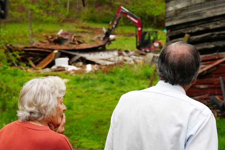 Property owners in McDowell County, North Carolina look on as their tobacco barn, which was in their family for over 100 years, is demolished as part of their private property debris removal request to the U.S. Army Corps of Engineers, April 24, 2025. The structure was damaged in Hurricane Helene and presented a safety concern requiring it to be torn down and removed.