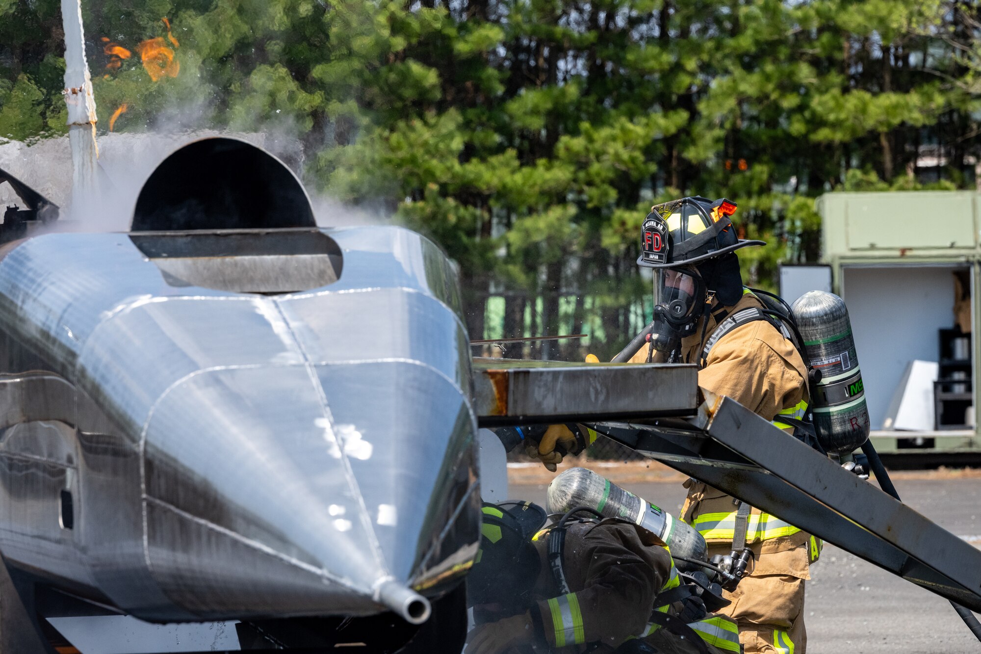 Firefighters watch the flames of an F-16 fire trainer.