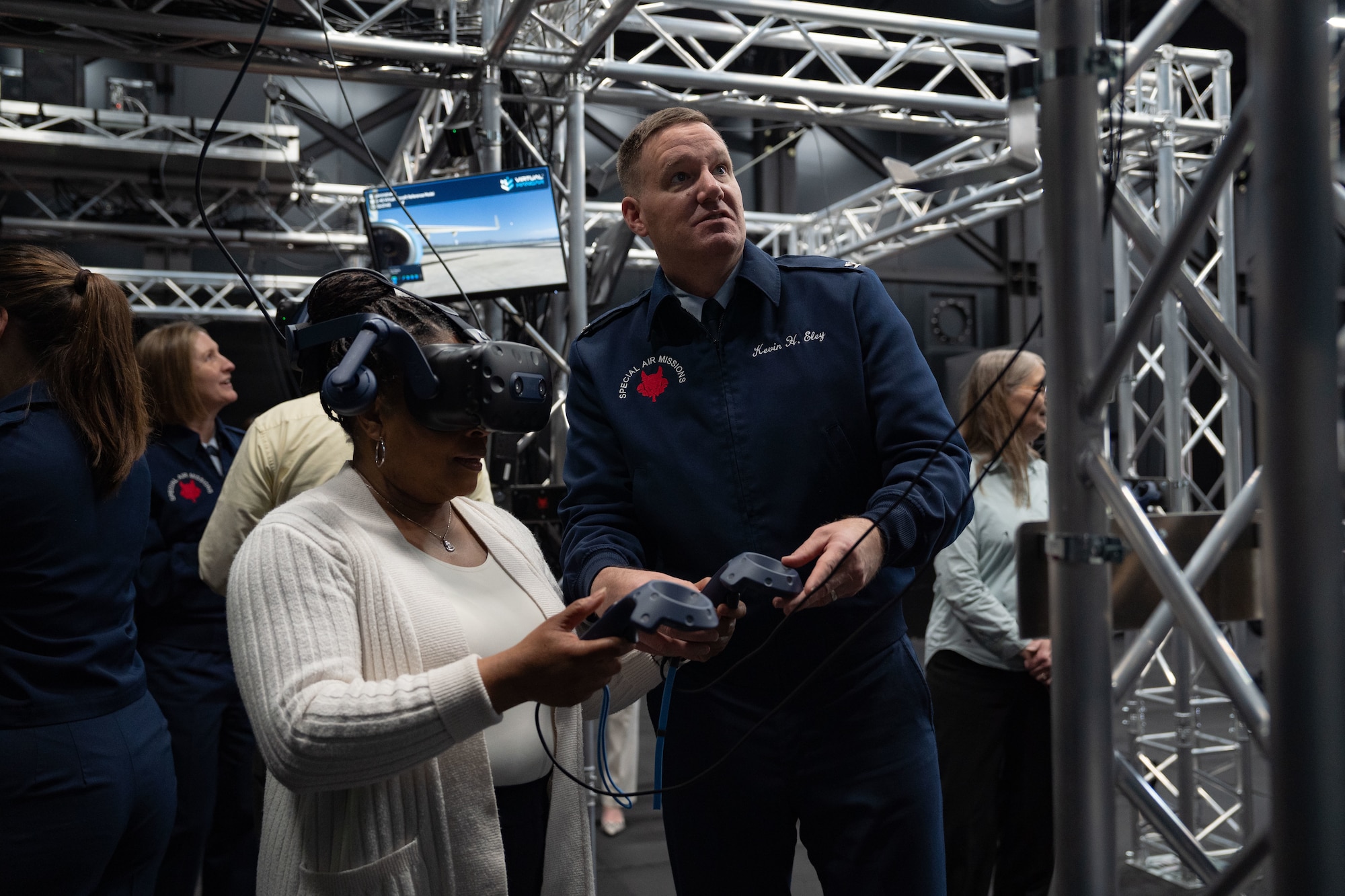 Col. Kevin Eley, 89th Operations Group commander, assists an honorary commander with operating a virtual reality headset during an Honorary Commander immersion tour of the 89th Airlift Wing at Joint Base Andrews, Maryland, April 8, 2025. Attendees received a one-of-a-kind mission brief, a hands-on virtual reality headset experience walking through our aircraft, and toured a C-37 and C-40 aircraft. (U.S. Air Force photo by Staff Sgt. Gabrielle Winn)