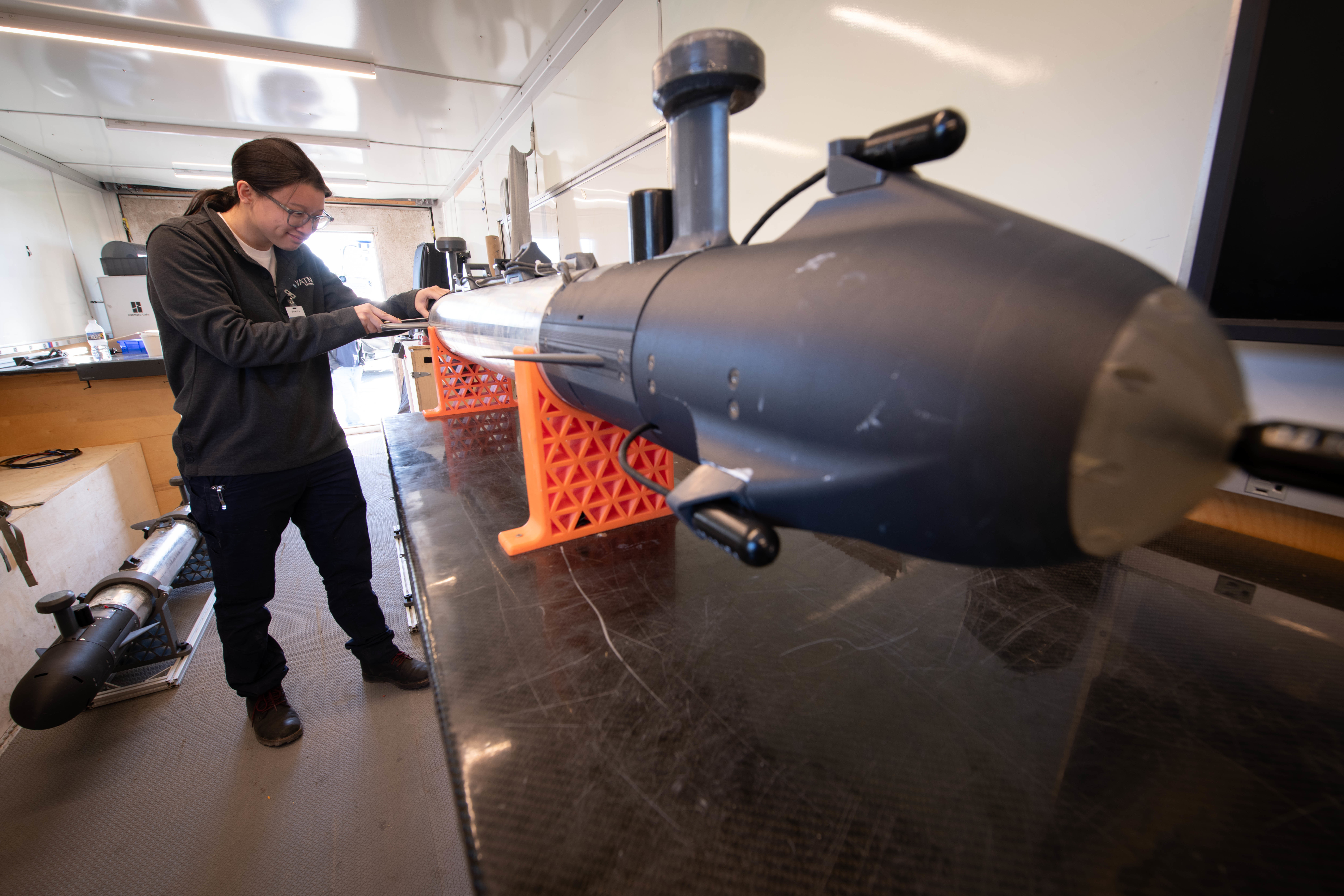 Female engineer examining a sensor torpedo.