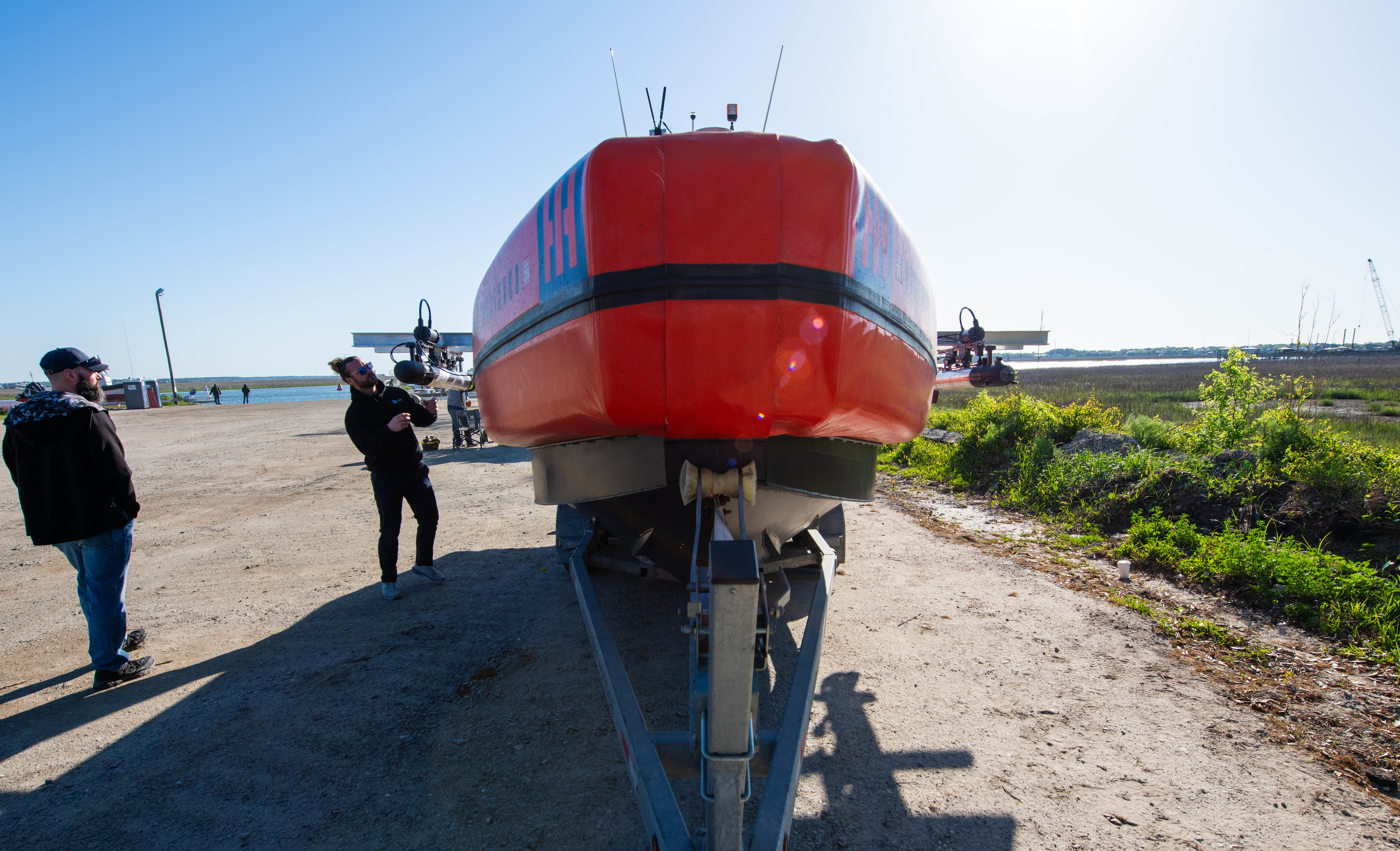 Shot of a nose of a boat with two men standing near by, examining the boat.