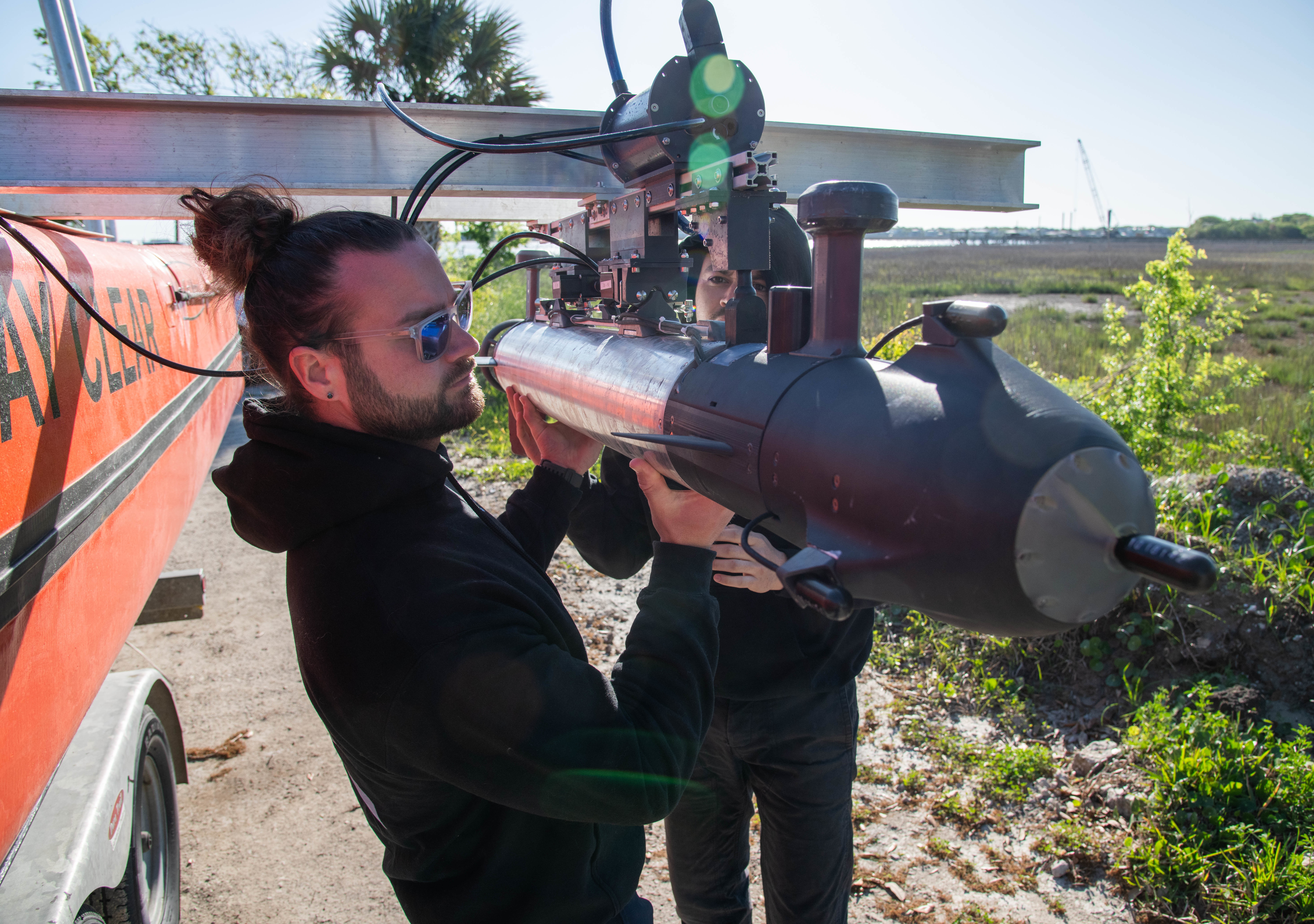 Two team members holding up a sensor torpedo.