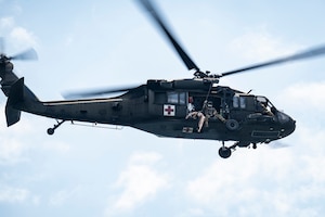 A HH-60L Black Hawk assigned to the United States Army Air Ambulance Detachment (USAAAD), 1st Battalion, 228th Aviation Regiment Joint Task Force-Bravo, flies by with a crew chief during a simulated overwater hoist rescue at Lake Yojoa, Honduras, April 22, 2025. To conduct a rescue, two pilots fly with a crew chief who operates the hoist, and a flight paramedic who assists with rescue and initial care of the patient. (U.S. Air Force photo by Staff Sgt. Sadie Colbert)