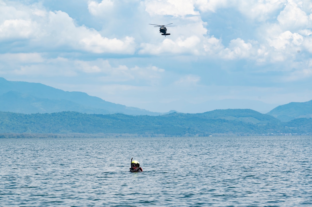 U.S. Army Dr. (Lt. Col.) Brittany Janssen, Army Forces Battalion flight surgeon, acts as a patient during a simulated overwater hoist rescue at Lake Yojoa, Honduras, April 22, 2025. Created by a volcanic eruption, Lake Yojoa is the largest lake in Honduras, with a surface area of 31 square miles, making it an optimal location for rescue practice. (U.S. Air Force photo by Staff Sgt. Sadie Colbert)