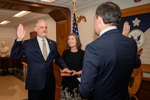 NCIS Deputy Director Gregory A. Scovel, Jr. takes the oath of office while his wife, Gigi looks on.