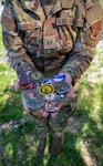 U.S. Air National Guard Technical Sgt. Jamie Gardner, 190th Air Refueling Wing, receives a collection of military challenge coins at Rosecrans Air National Guard Base, Missouri, April 16, 2025. The coins were awarded in recognition of her selection as the Region 5 Noncommissioned Officer of the Year during the Air National Guard Outstanding Airmen of the Year competition.