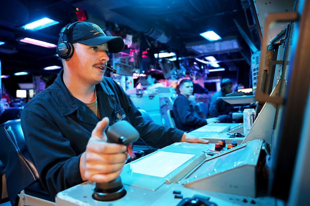 A sailor works in a command center aboard a ship.